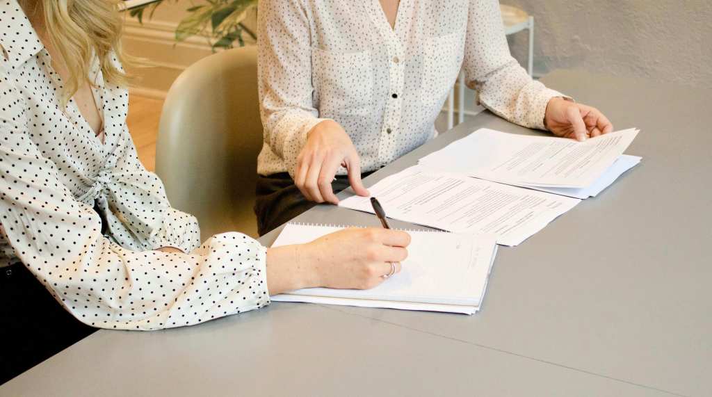 A woman who is taking notes while another woman explains her the contract