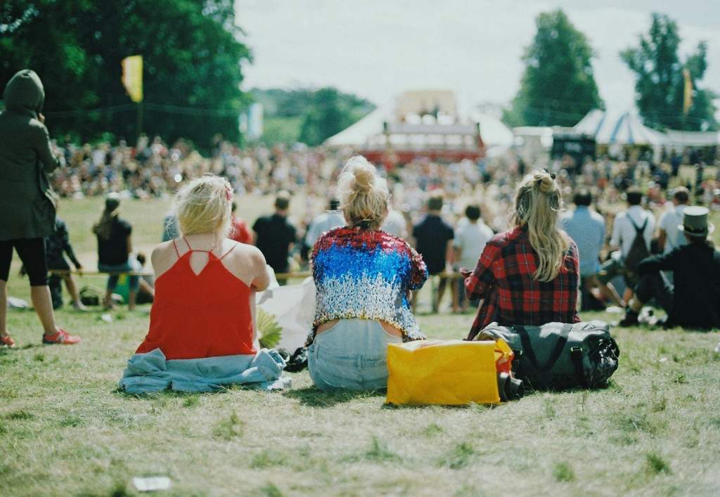 3 friends who are sitting on a meadow at a festival